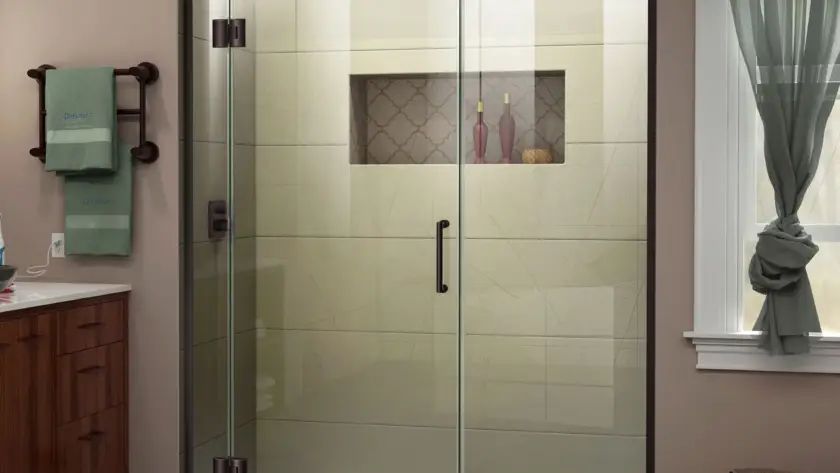 Hinged shower door with clear glass panels and matte black hardware in a modern bathroom with beige walls and a tiled shower.