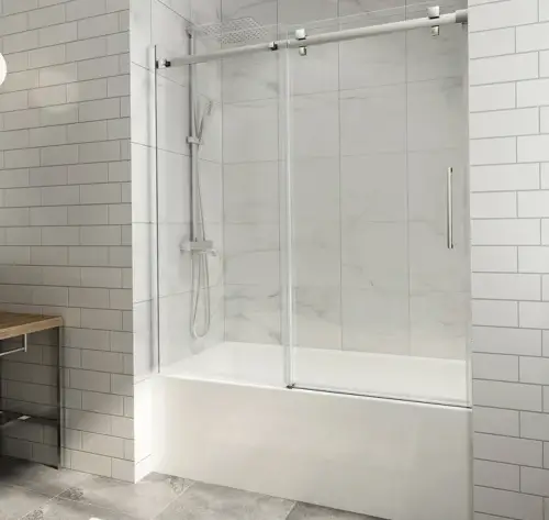 Sliding bathtub shower door with clear glass panels and polished chrome hardware in a modern bathroom with white subway tiles.