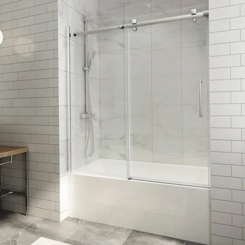 Sliding bathtub shower door with clear glass panels and polished chrome hardware in a modern bathroom with white subway tiles.